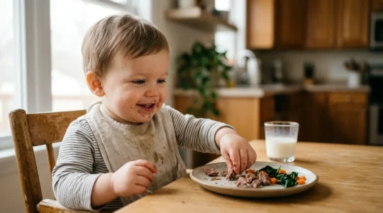Young toddler with healthy meal rich in iron sources alongside glass of milk on table