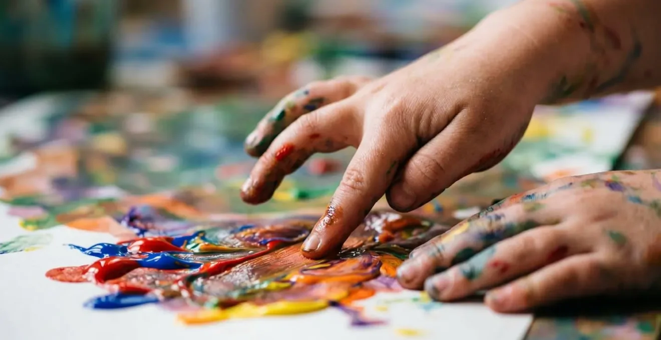 Young child's hands freely exploring colorful paint textures in an unstructured creative process