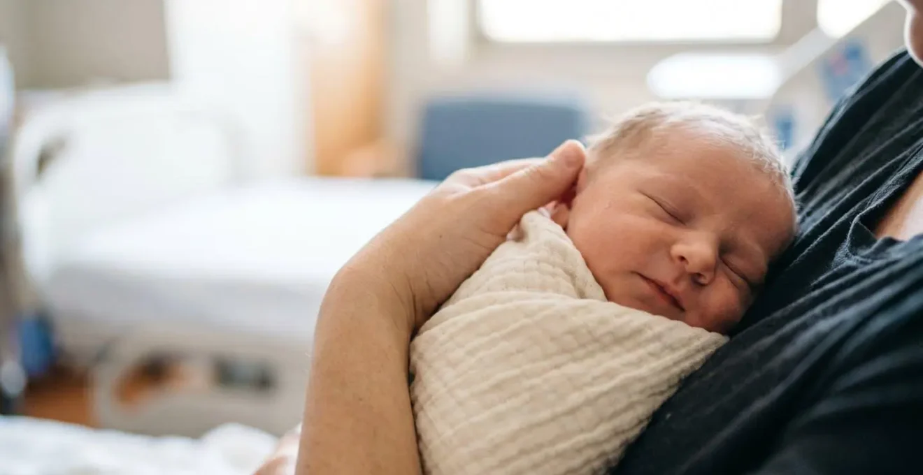 Swaddled newborn baby being comforted during medical procedure using evidence-based soothing techniques